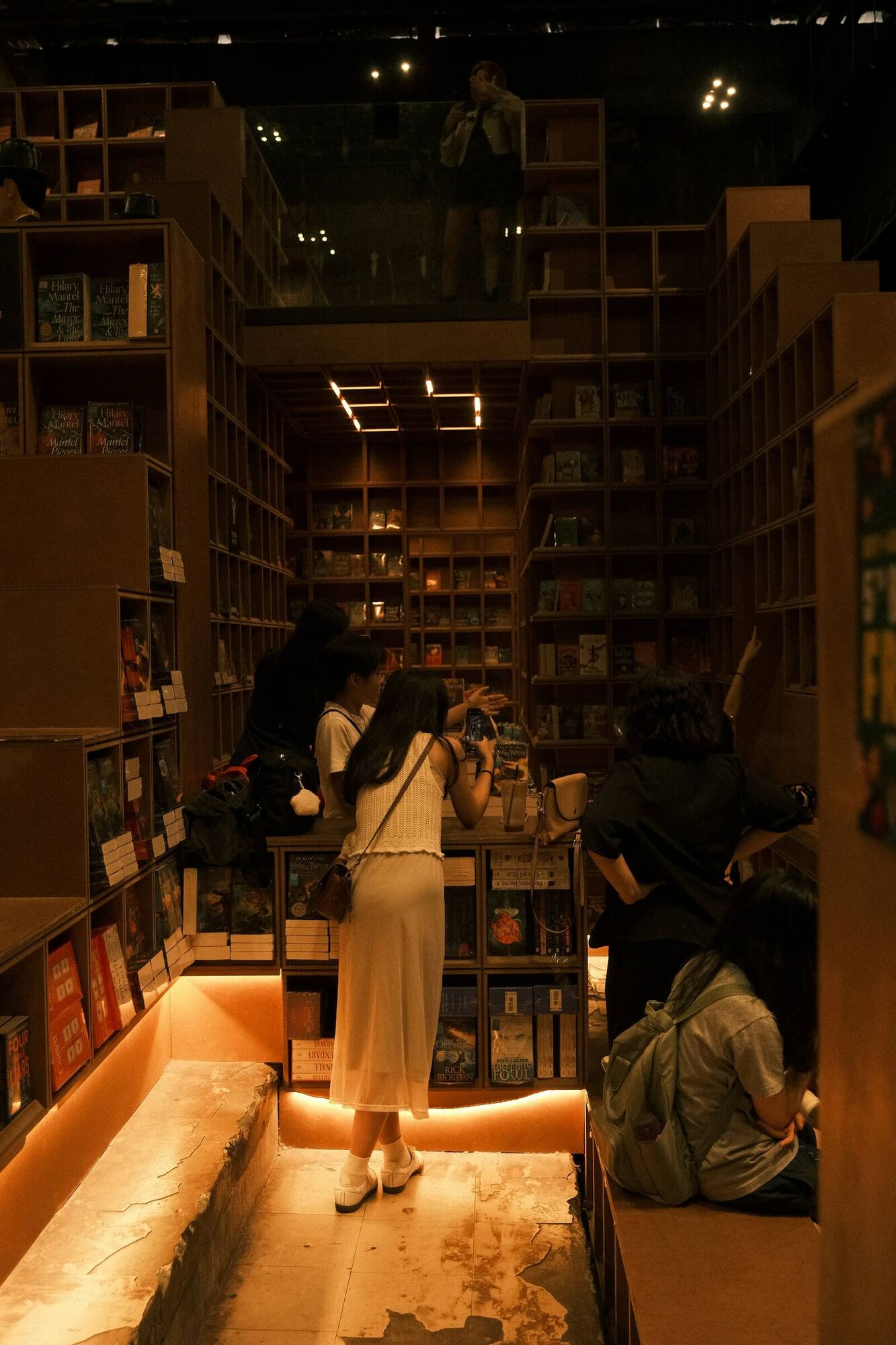 Lectores mirando las baldas de una librería con luz cálida